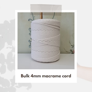 Op de afbeelding: Een close-up van een witte, 4 mm macramé koord, opgerold tot een bal. Het koord is gemaakt van natuurlijke vezels en is perfect voor knutselprojecten.