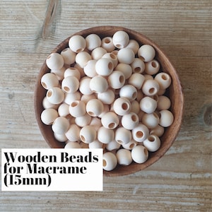 Puede incluir: Un bol lleno de cuentas de madera natural de 15 mm de diámetro, con un agujero en el centro de cada cuenta. Las cuentas son perfectas para proyectos de macramé.