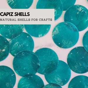 Può includere: Una collezione di conchiglie Capiz color turchese, perfette per l'artigianato. Le conchiglie sono rotonde con una finitura naturale e iridescente. Il testo "CAPIZ SHELLS NATURAL SHELLS FOR CRAFTS" è visualizzato su sfondo bianco.