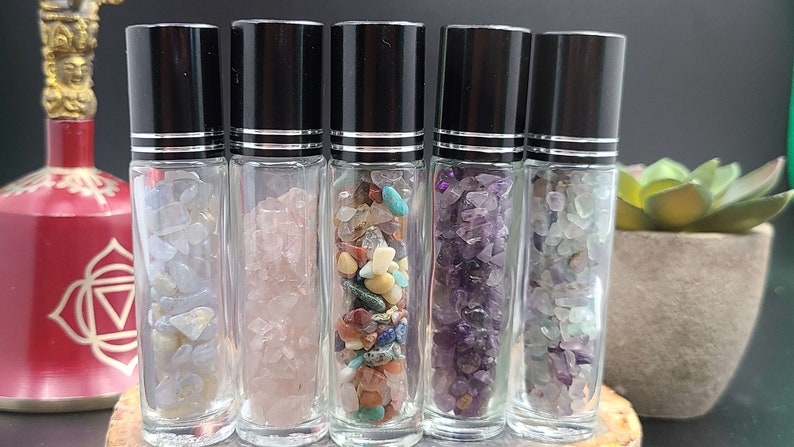 5 roller bottle in a row filled with different types of crystal chips.
