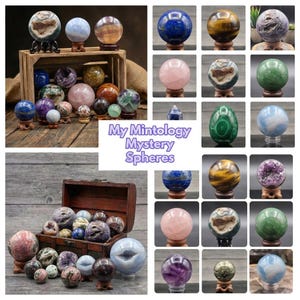May include: A collection of various mineral spheres and geodes displayed in wooden crates and chests, featuring diverse colors and textures including blue, pink, green, and purple stones. The text My Mintology Mystery Spheres is centered.