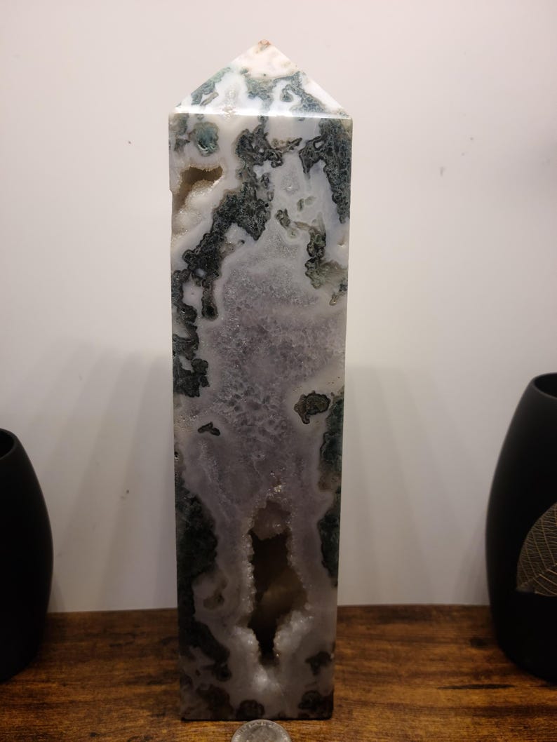 May include: A tall, white, green, and purple agate crystal point with a large, open cavity. The crystal is polished and has a smooth, glassy surface.