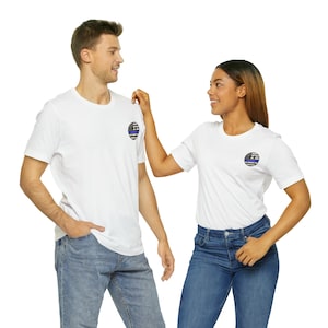 Peut inclure: Deux t-shirts blancs avec un motif de drapeau américain à ligne bleue sur la poitrine gauche. Les chemises sont portées par deux personnes debout face à face.