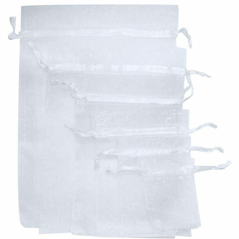 Pu&ograve; includere: Un set di sei sacchetti regalo in organza bianca con coulisse. I sacchetti sono impilati uno sopra l'altro, con il sacchetto pi&ugrave; grande in basso e il pi&ugrave; piccolo in alto.