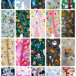 Op de afbeelding: Een collectie van twintig babyslaappakjes met diverse kleurrijke patronen, waaronder Disney-figuren, vakantiethema's, bloemenprints, hartjes, strikjes en seizoensgebonden motieven, elk voorzien van een centrale verticale ritssluiting.