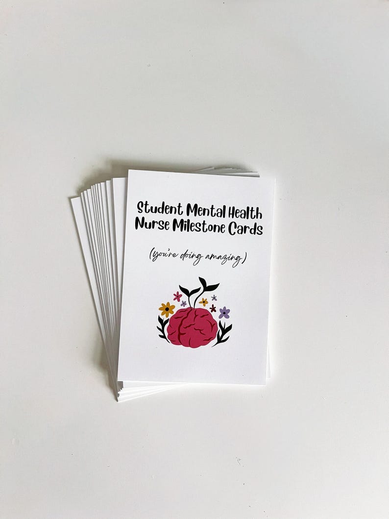 K&ouml;nnte beinhalten: Ein Stapel wei&szlig;er Karten mit dem Text "Student Mental Health Nurse Milestone Cards" und dem Satz "(you're doing amazing)". Das Kartendesign zeigt ein rosa Gehirn, umgeben von Blumen und Bl&auml;ttern.