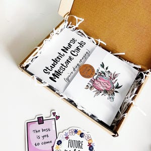 Peut inclure: Une bo&icirc;te cadeau contenant des "cartes &eacute;tapes pour infirmi&egrave;res &eacute;tudiantes" et une carte avec un motif de c&oelig;ur floral. Sont &eacute;galement inclus des autocollants avec les inscriptions "Le meilleur est &agrave; venir" et "FUTURE nurse".