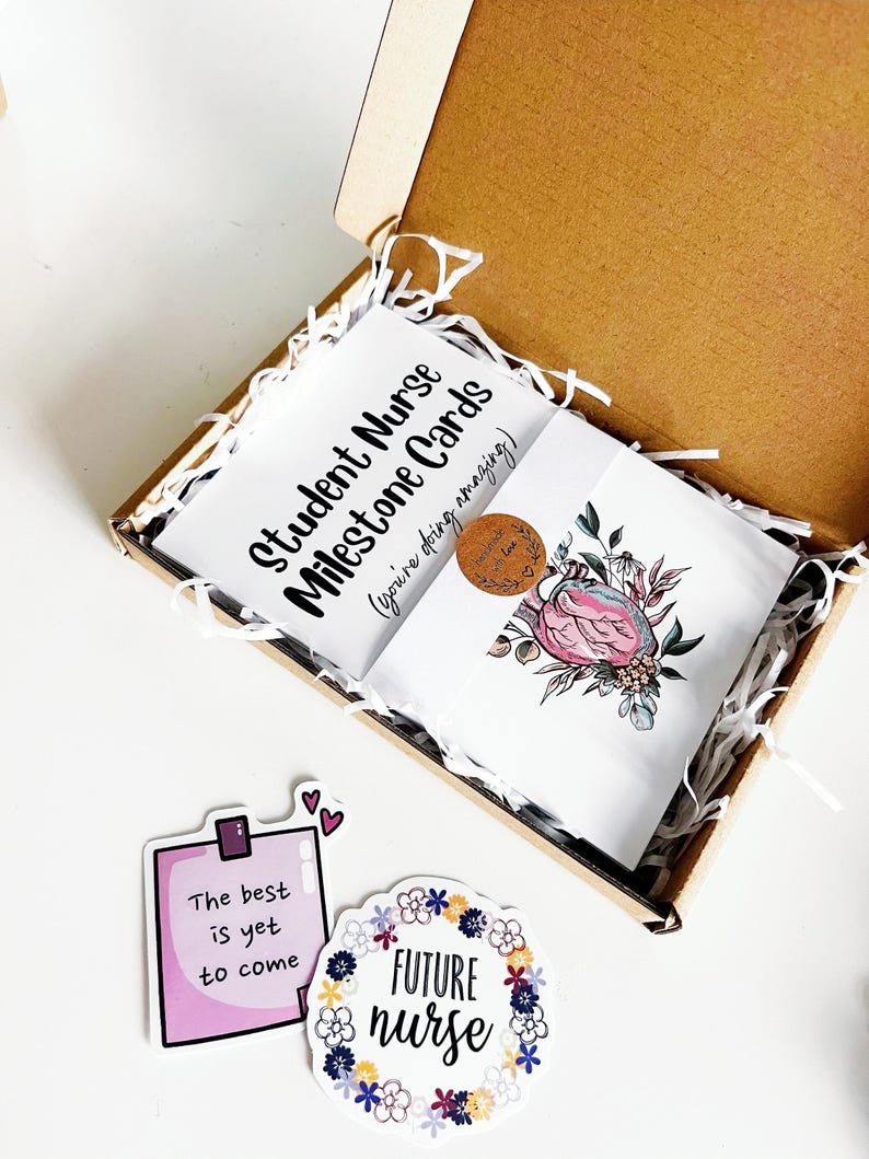 Peut inclure: Une bo&icirc;te cadeau contenant des "cartes &eacute;tapes pour infirmi&egrave;res &eacute;tudiantes" et une carte avec un motif de c&oelig;ur floral. Sont &eacute;galement inclus des autocollants avec les inscriptions "Le meilleur est &agrave; venir" et "FUTURE nurse".