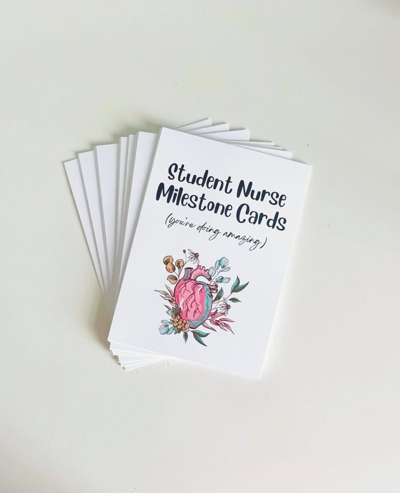 Peut inclure: Un ensemble de cartes blanches &laquo;&nbsp;Student Nurse Milestone Cards&nbsp;&raquo; avec le texte &laquo;&nbsp;Student Nurse Milestone Cards (you're doing amazing)&nbsp;&raquo;. Les cartes pr&eacute;sentent une illustration d'un c&oelig;ur humain entour&eacute; de fleurs et de feuilles.