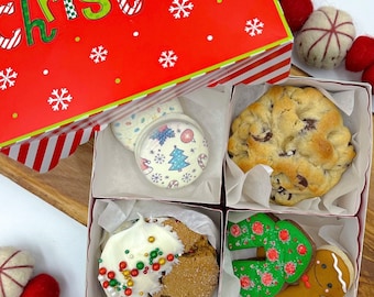 May include: A red and white striped gift box with the words "Merry Christmas" on the lid. The box contains four individual compartments, each containing a different cookie. The cookies are a chocolate chip cookie, a gingerbread cookie with white frosting and sprinkles, a sugar cookie with white frosting and a Christmas tree design, and a gingerbread cookie shaped like a Christmas tree.