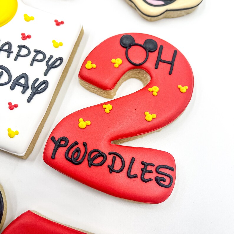 May include: Red and white Mickey Mouse themed cookie decorated with black icing and the number "2" and the words "WODLES OH".