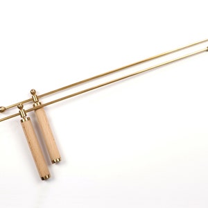 Peut inclure: Deux tiges en laiton avec des poignées en bois. Les tiges ont une boule à chaque extrémité. Les poignées sont en bois brun clair.