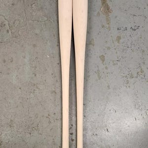 May include: Two wooden baseball bats, unpainted, with rounded ends.