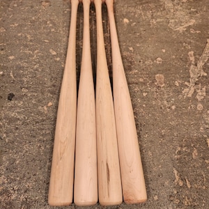 May include: Four unfinished wooden baseball bats with rounded ends.