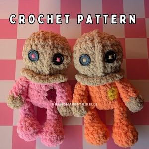 May include: Two handmade crochet dolls. One doll is pink with a brown head and collar, and the other is orange with a brown head and collar. Both dolls have button eyes and a heart-shaped patch. The text "CROCHET PATTERN" is at the top.