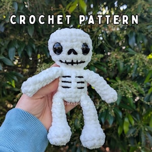 Op de afbeelding: Een witte pluche skeletpop met grote zwarte plastic ogen en geborduurde zwarte draaddetails voor de neus, mond en ribbenkast. De tekst CROCHET PATTERN staat in witte letters bovenaan de afbeelding tegen een achtergrond van groen gebladerte.