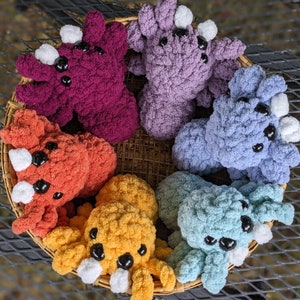 Puede incluir: Una colecci&oacute;n de siete peluches de pulpo de crochet en varios colores, incluyendo morado, naranja, azul y amarillo. Los peluches est&aacute;n dispuestos en c&iacute;rculo sobre una cesta tejida.