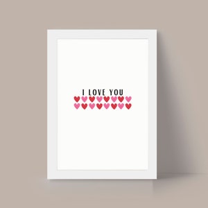 May include: White framed print with the text "I LOVE YOU" in black lettering and a row of pink and red hearts.