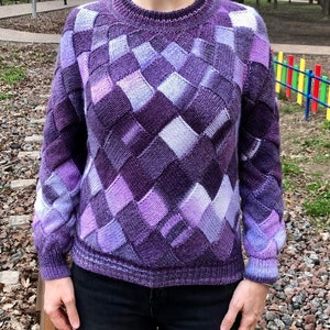 May include: A purple and lavender knitted jumper with a geometric diamond pattern.