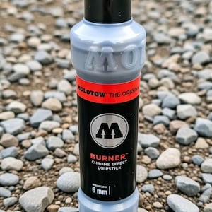 Pode incluir: Um marcador preto Molotow Burner Chrome Effect Dripstick com ponta de 6 mm. O marcador tem uma tampa preta e um corpo cinza com texto vermelho e branco. Projetado para aplicações de alto fluxo.