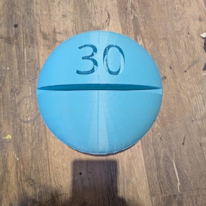 May include: A light blue pill-shaped object with the number 30 printed on it.