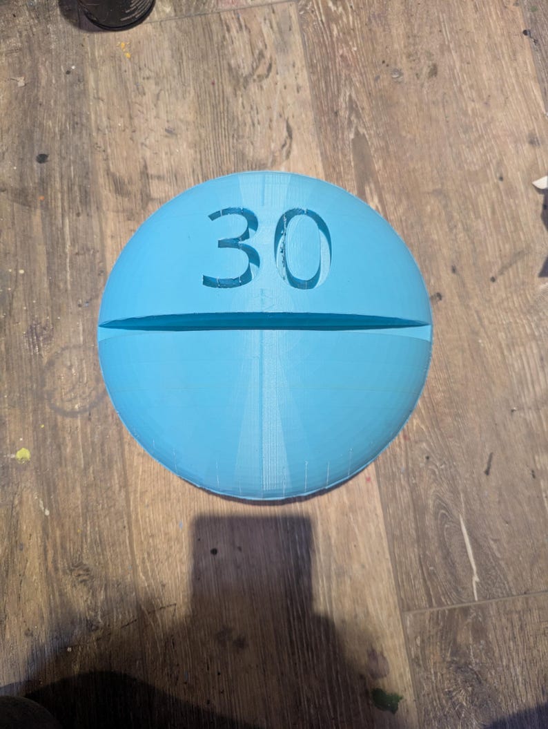 May include: A light blue pill-shaped object with the number 30 printed on it.