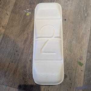 May include: White plastic pill organizer with four compartments. The number "2" is embossed on the front.
