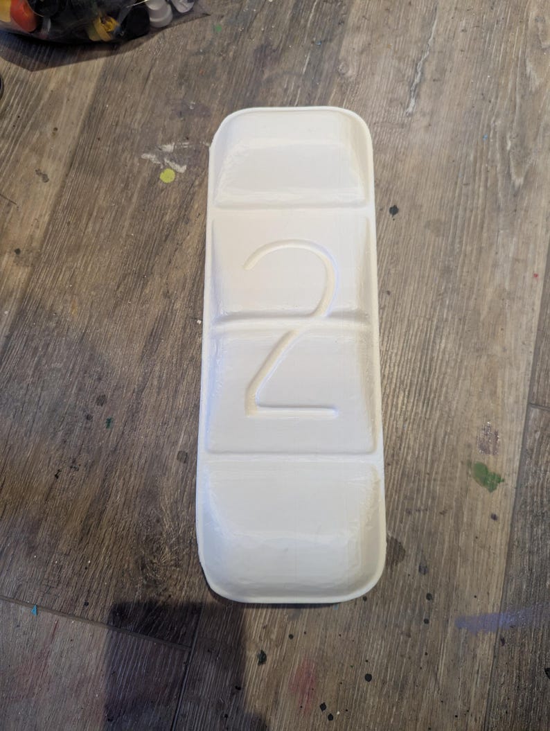 May include: White plastic pill organizer with four compartments. The number "2" is embossed on the front.