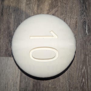 May include: A white round disc with the number "10" embossed on it.