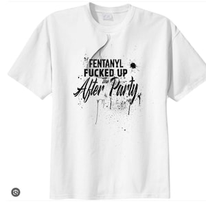 Puede incluir: Camiseta blanca con el texto "FENTANYL FUCKED UP The After Party" en negro, con una fuente estilizada. El diseño incluye salpicaduras y efectos de goteo negros. La camiseta tiene cuello redondo y mangas cortas.