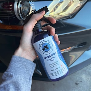 Pode incluir: Uma garrafa de spray azul escuro rotulada como "Deep Dive Surface Prep Spray" da Whale Wax Co. A garrafa tem um bico de spray preto e um rótulo branco com texto e um logotipo de baleia. Fabricado nos EUA.