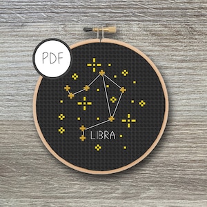 May include: Black and gold cross-stitch pattern of the Libra constellation with the word "LIBRA" in gold thread.