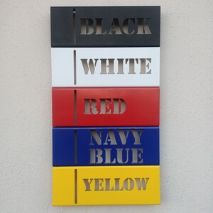 May include: Five metal rectangular signs with different colors and the words "BLACK", "WHITE", "RED", "NAVY BLUE", and "YELLOW" written in white.
