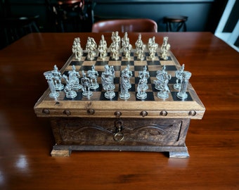 May include: A wooden chessboard with a carved design and a brass latch. The board is set up with silver and gold chess pieces.