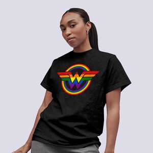 May include: Black t-shirt featuring a rainbow Wonder Woman logo. The logo is a circle with a rainbow design and a stylised "W" inside.