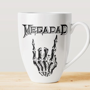 Może przedstawiać: Biały ceramiczny kubek do kawy z czarno-białym nadrukiem szkieletu dłoni wykonującego gest rock and roll. Tekst "MEGADETH" jest nadrukowany nad dłonią.