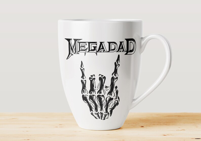 Może przedstawiać: Biały ceramiczny kubek do kawy z czarno-białym nadrukiem szkieletu dłoni wykonującego gest rock and roll. Tekst "MEGADETH" jest nadrukowany nad dłonią.