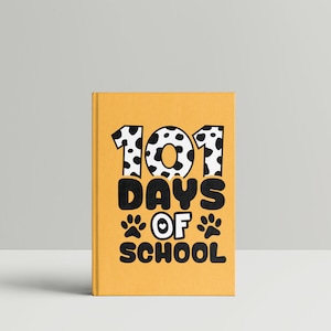 K&ouml;nnte beinhalten: Gelbes Buch mit dem Text "101 Days of School" in Schwarz mit einem schwarz-wei&szlig;en Tupfenmuster um die Zahlen. Der Text enth&auml;lt auch zwei schwarze Pfotenabdr&uuml;cke mit einem Herzen in der Mitte.