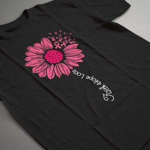 May include: Black t-shirt with a pink sunflower design and the text "Faith Hope Love" written vertically on the right side of the shirt.