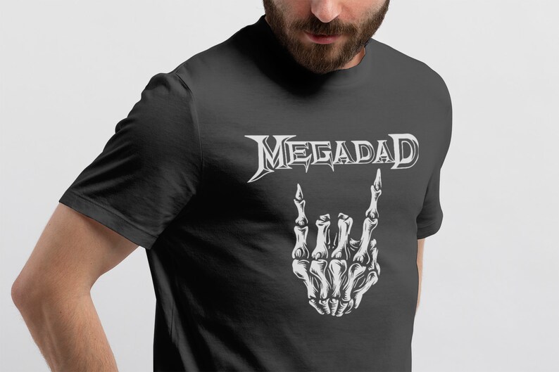 Może przedstawiać: Czarny T-shirt z białym nadrukiem szkieletu dłoni wykonującego znak rock and roll. Tekst "MEGADETH" znajduje się nad dłonią.