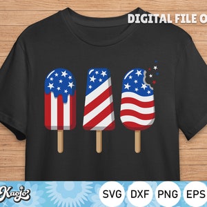 May include: A black t-shirt with a graphic of three red, white, and blue popsicles. The popsicles are shaped like the American flag. The popsicle on the right has a bite taken out of it.