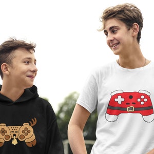 May include: Two people wearing shirts with a video game controller design. One shirt is black with a brown controller and reindeer antlers. The other shirt is white with a red controller and a Santa hat.