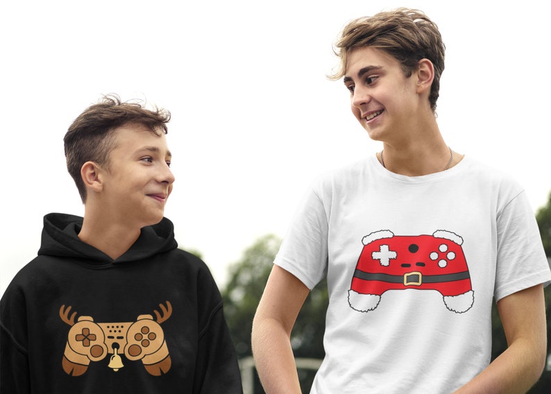 May include: Two people wearing shirts with a video game controller design. One shirt is black with a brown controller and reindeer antlers. The other shirt is white with a red controller and a Santa hat.
