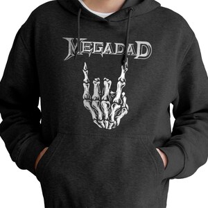 Może przedstawiać: Szara bluza z kapturem z nadrukiem nazwy zespołu "Megadeth" w kolorze białym na przodzie. Logo zespołu przedstawia białą szkieletową dłoń wykonującą gest rock and roll.