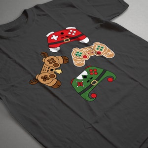 May include: A dark gray t-shirt with a design of four video game controllers dressed up as Christmas characters. The controllers are dressed as Santa, a gingerbread man, an elf, and a reindeer.