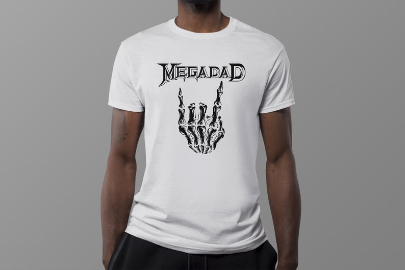 Może przedstawiać: Biała koszulka z czarnym nadrukiem szkieletu dłoni wykonującego znak rock and roll i napisem "Megadeth" nad nim.