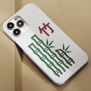 May include: White phone case featuring a green bamboo design and the Chinese character "竹" in red. The case has a glossy finish and a camera cutout with three lenses.