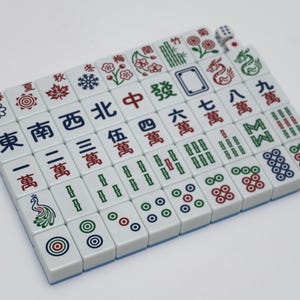 May include: A complete set of white Mahjong tiles with blue edges, featuring Chinese characters and symbols in red, green, and black. Includes dice. A classic board game.