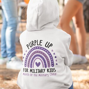 May include: White hooded sweatshirt with a purple rainbow and the text "Purple Up for Military Kids Month of the Military Child".