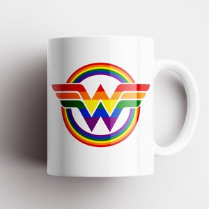 May include: White ceramic mug featuring a rainbow-coloured Wonder Woman logo. The logo depicts a stylised "W" with wings and a rainbow circle surrounding it.